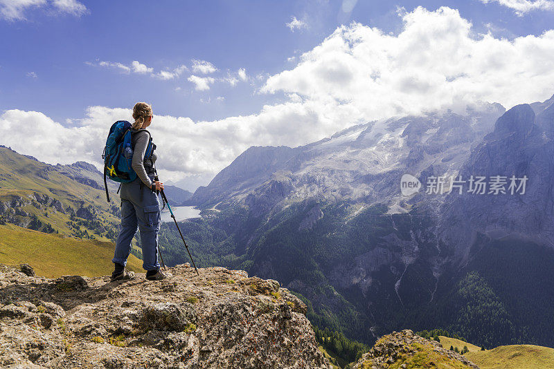 意大利北部Dolomites的Viel dal Pan小路上，一位老妇人正在欣赏美丽的Fedaia湖和Marmolada湖。